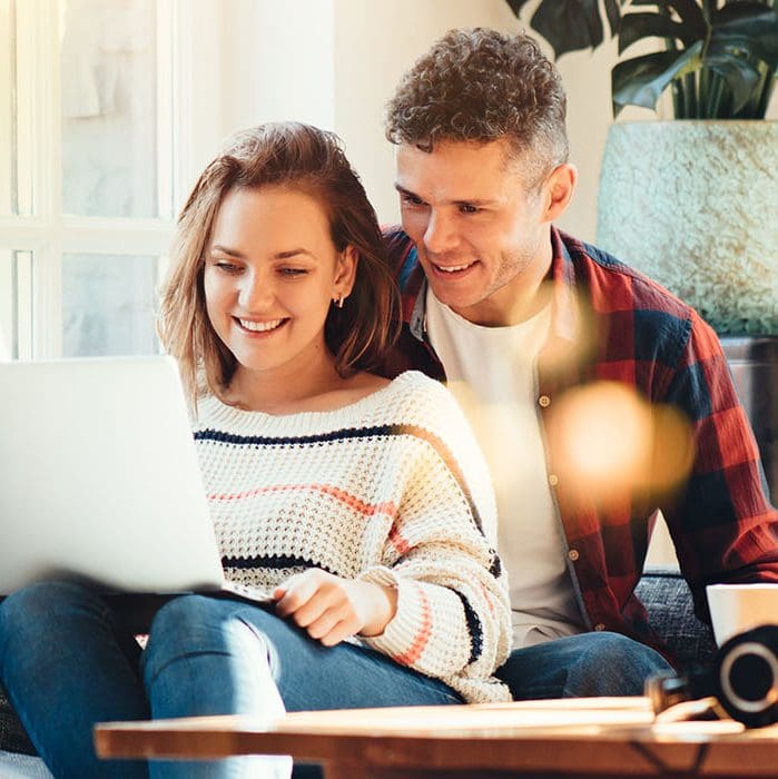 kvinna och man sitter i soffan och tittar på laptop